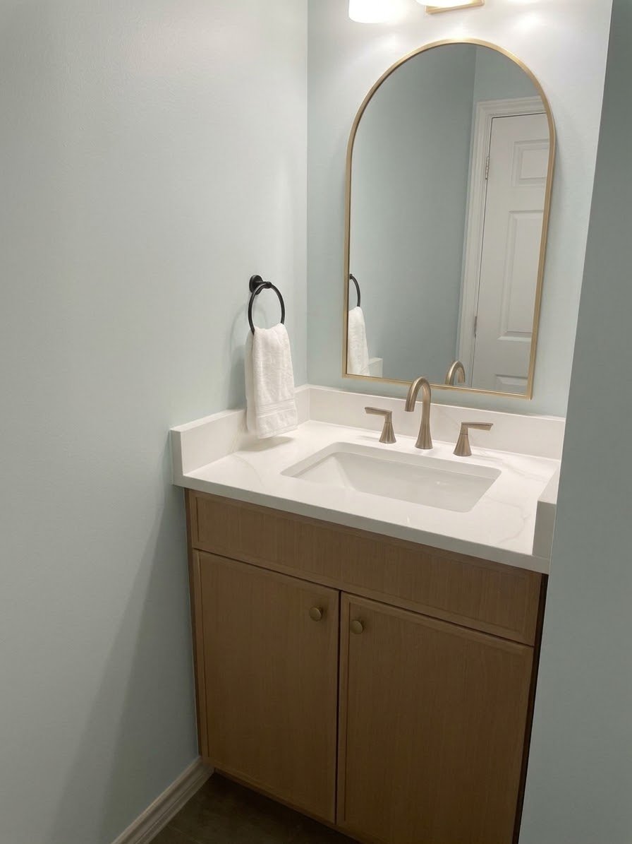 Custom powder room vanity cabinetry with arched mirror
